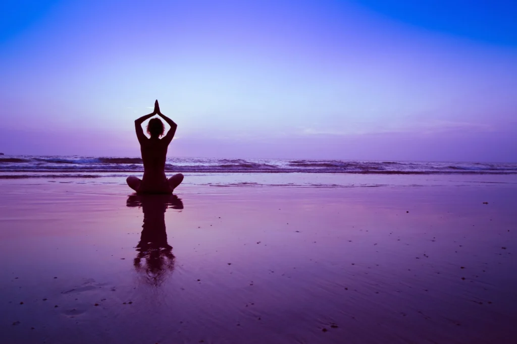 figura di donna che fa yoga di fronte al mare